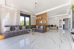Ein modernes Wohnzimmer mit einem grauen Ecksofa, einem Glastisch und einer Holz-Akzentwand.