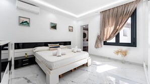 Een moderne slaapkamer met een bed, nachtkastjes, een bureau en een raam met gordijnen.