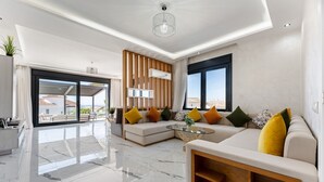 Een moderne woonkamer met een hoekbank, een glazen salontafel en uitzicht op de stad.