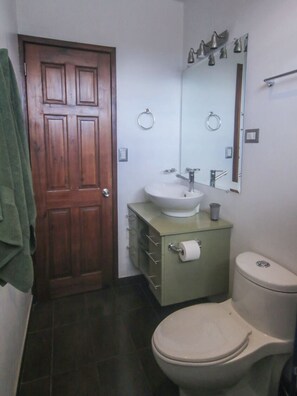 A bathroom with a wooden door, a sink, a toilet, and a mirror. - Cozy and central apartment near Plaza del Sol (Freses)