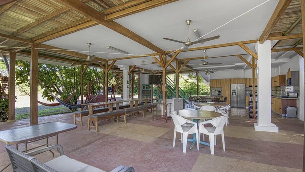 An open-plan kitchen and dining area with wooden beams, a ceiling fan, and a view of the outdoors. - Paso de Lapas: Surrounded by Nature & Pool (Lagunillas)