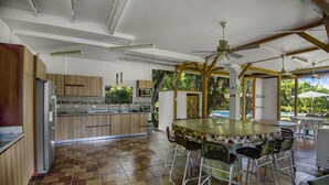 A kitchen with a central island, bar stools, ceiling fans, and a view of the outdoors. - Paso de Lapas: Surrounded by Nature & Pool (Lagunillas)