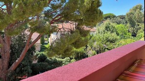 A balcony with a red umbrella, a pine tree, and a view of houses and greenery. - 50 steps from the Ô (Saint-Cyr-sur-Mer)