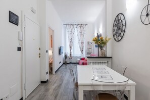 A hotel room with a dining area, a TV, a clock, and a window with curtains. - [Aquarium 5']Free Wifi & Netflix Prion by TILO (Genoa)