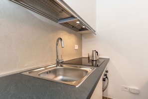 Een moderne keuken met een RVS spoelbak, een kraan, een koffiezetapparaat en een inbouw afzuigkap.