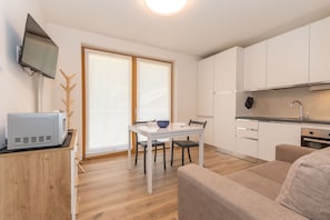 Een knus woongedeelte met kitchenette, eethoek en een bank.