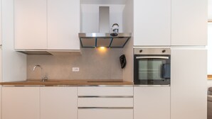 Eine moderne Küche mit Edelstahlgeräten, einem eingebauten Ofen und einer Holzausziehtafel.
