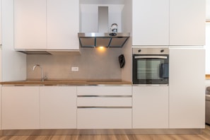 Eine moderne Küche mit Edelstahlgeräten, einem eingebauten Ofen und einer Holzausziehtafel.