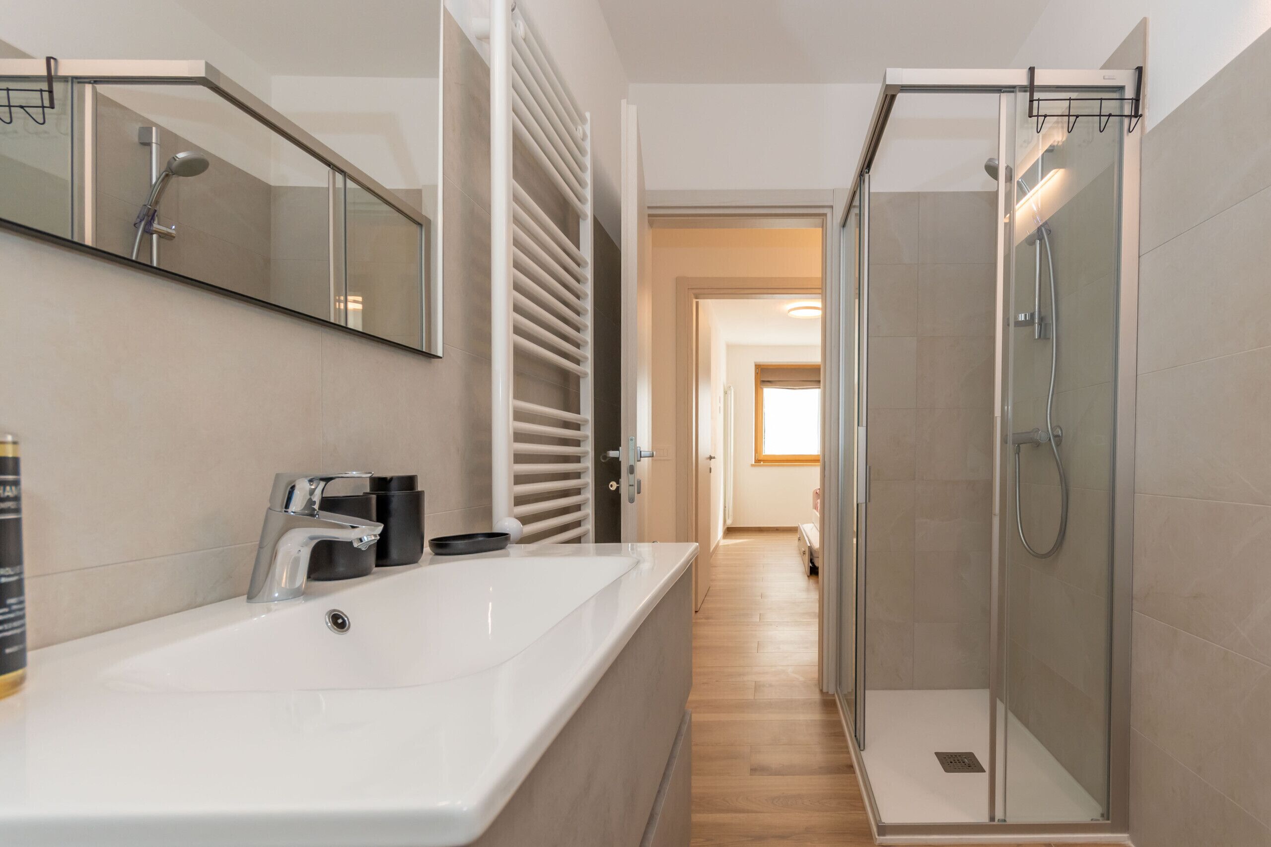 Ein modernes Badezimmer mit einem großen weißen Waschbecken, einer Duschkabine aus Glas und einer begehbaren Dusche.