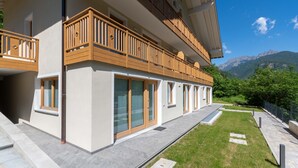 Ein modernes, zweistöckiges Gebäude mit Balkonen, großen Fenstern und Bergblick.