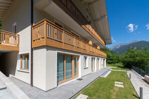Ein modernes, zweistöckiges Gebäude mit Balkonen, großen Fenstern und Bergblick.