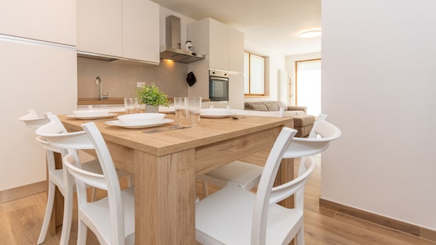 Eine moderne Küche mit einem Holztisch, weißen Stühlen und einem eingebauten Backofen.