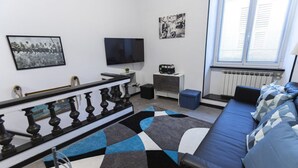 Una sala de estar moderna con un sofá, un televisor, un tapete estampado y obras de arte en las paredes.