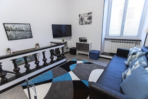 Ein modernes Wohnzimmer mit einer Couch, einem Fernseher, einem gemusterten Teppich und Kunstwerken an den Wänden.