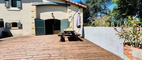 A building with a tiled roof, a wooden deck, and a small outdoor seating area with a table and chairs.