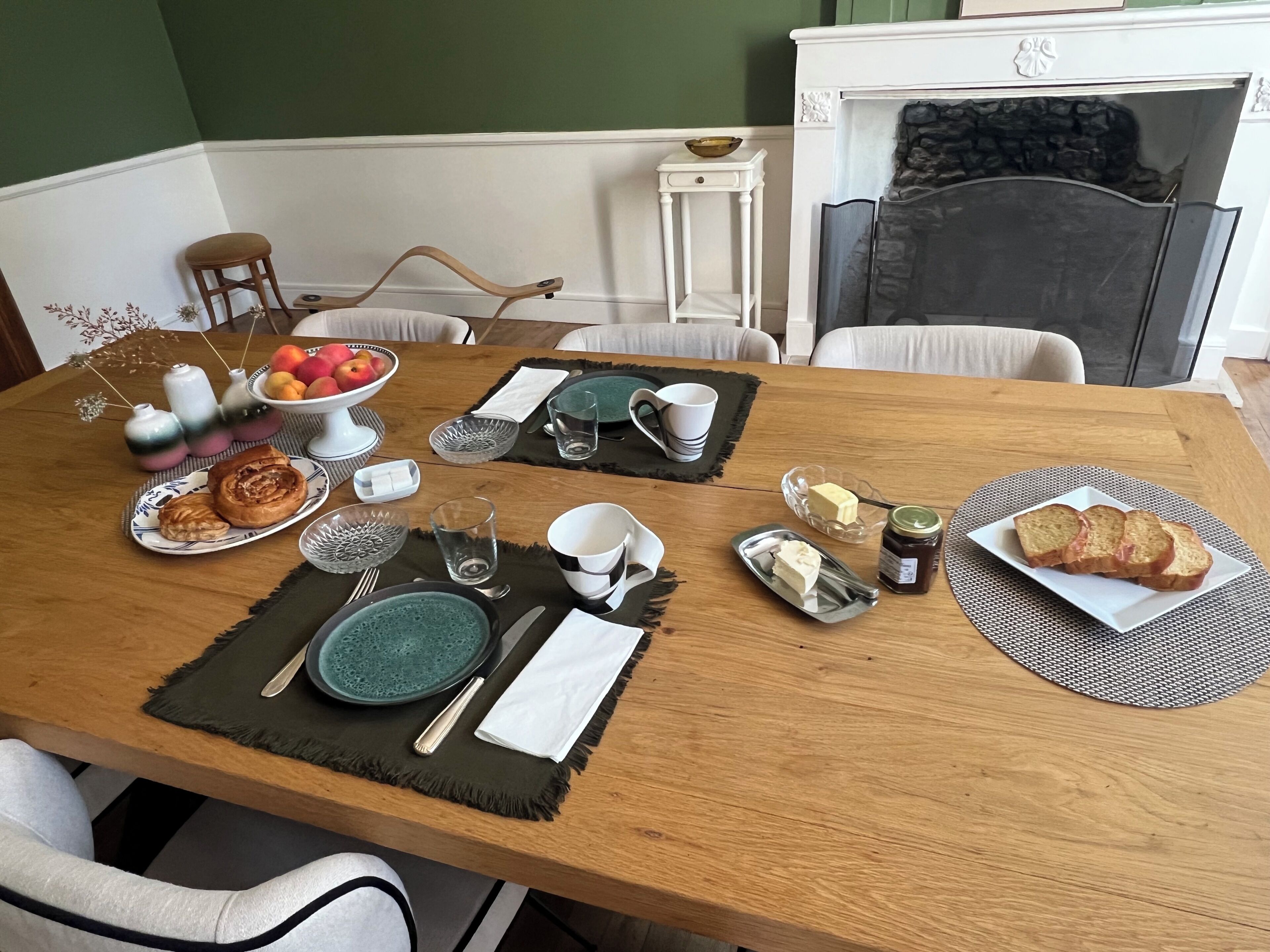 A dining table set with plates, bowls, cutlery, and a coffee pot, indicating a breakfast setting.