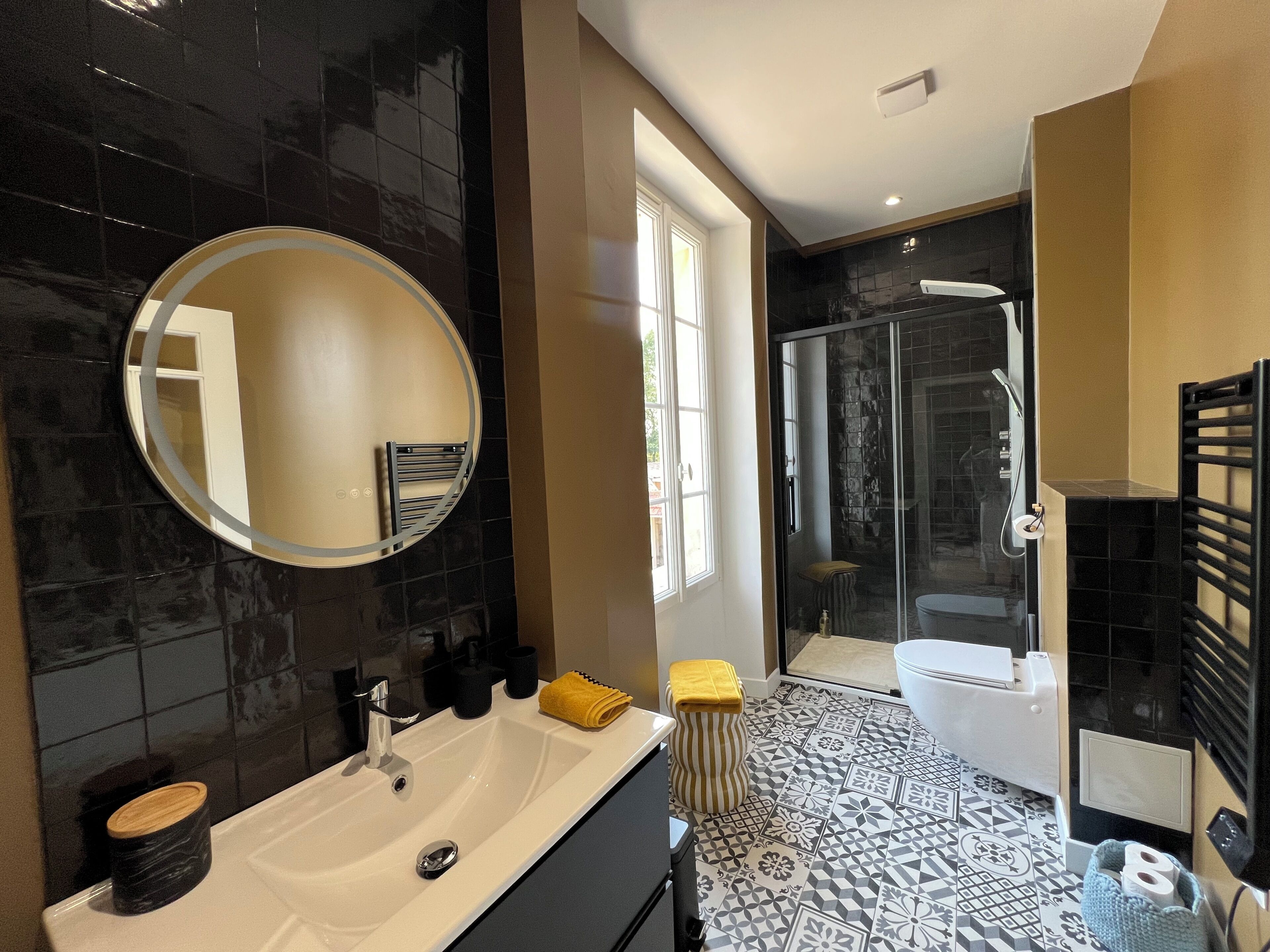 A modern bathroom with a large mirror, a sink, a toilet, and a shower area.