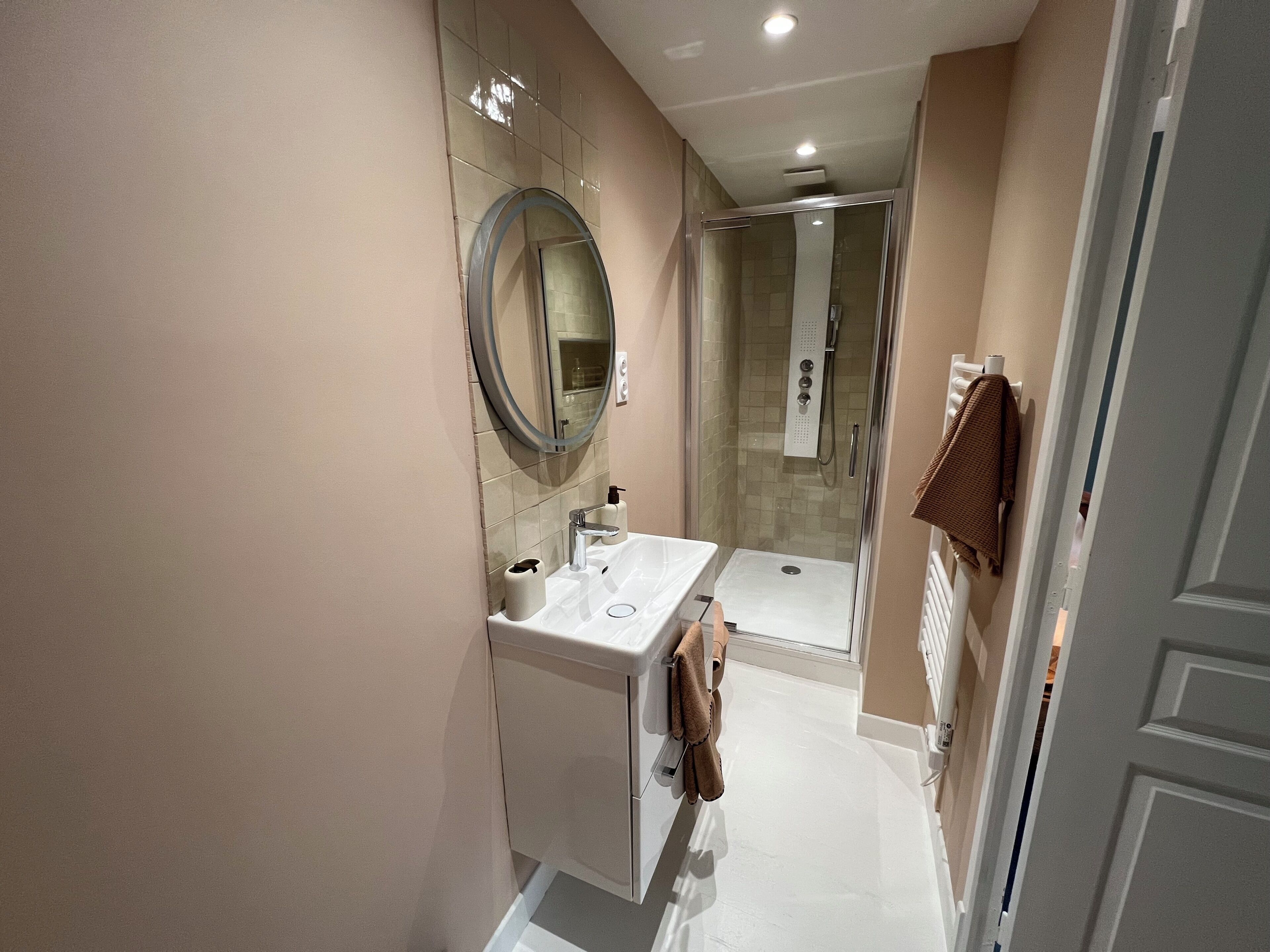 A modern bathroom with a sink, mirror, and shower.