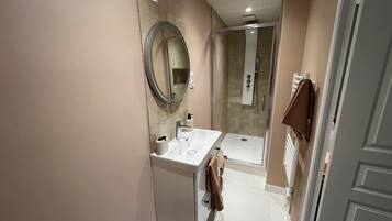 A modern bathroom with a sink, mirror, and shower.