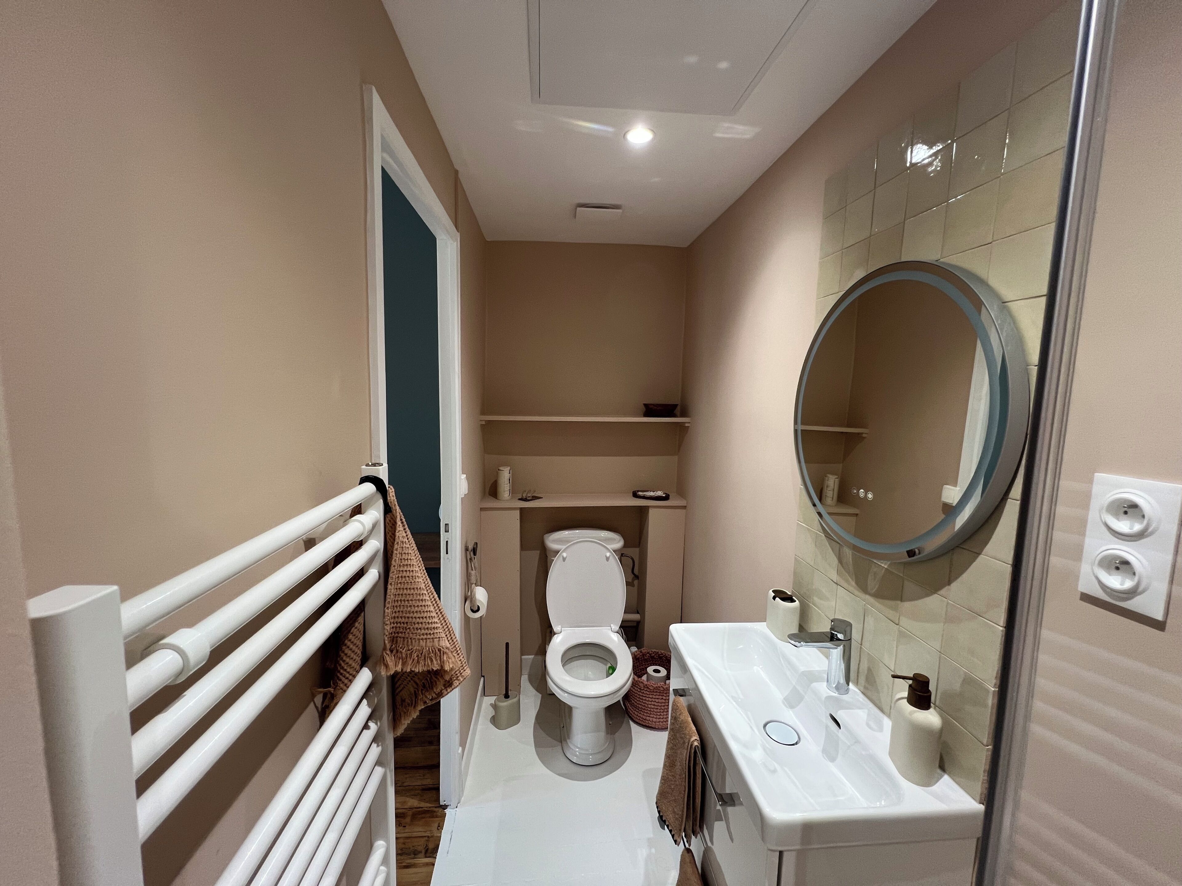 Een kleine badkamer met toilet, wastafel en spiegel.