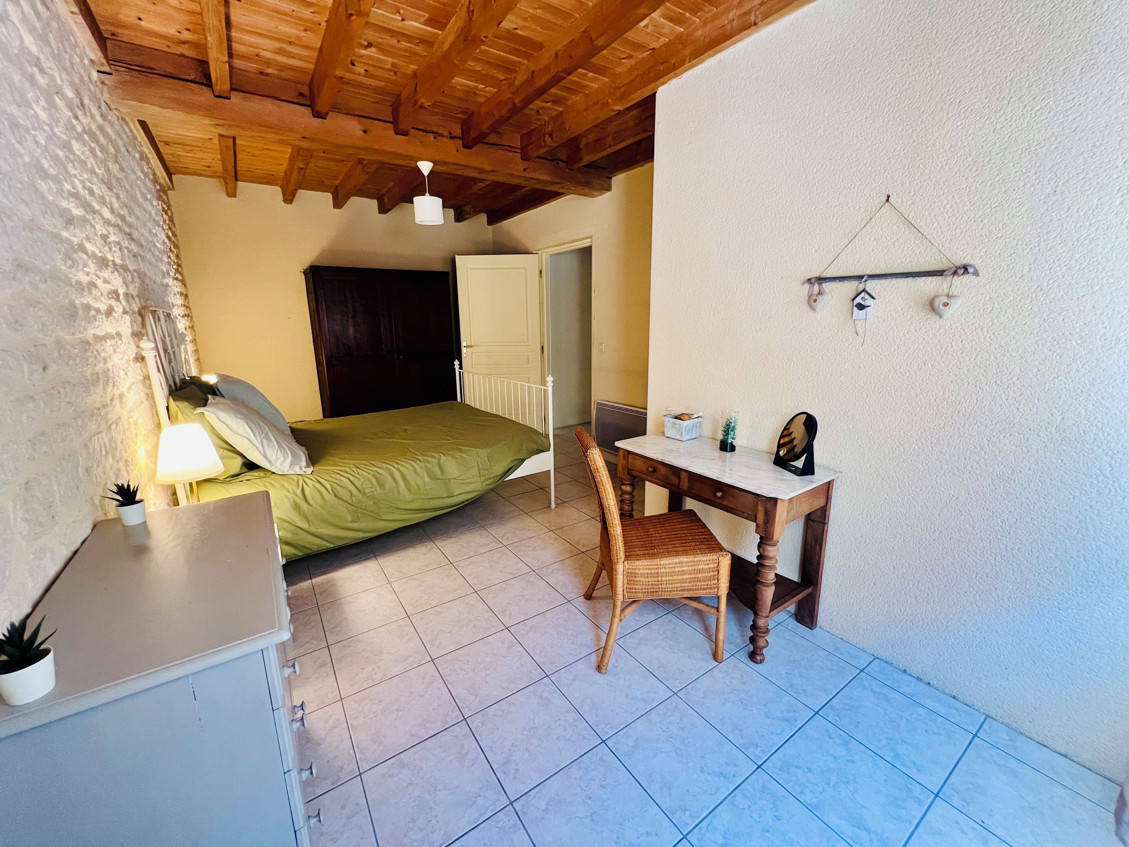 Ein Schlafzimmer mit Bett, Nachttisch, Lampe und einer kleinen Topfpflanze.
