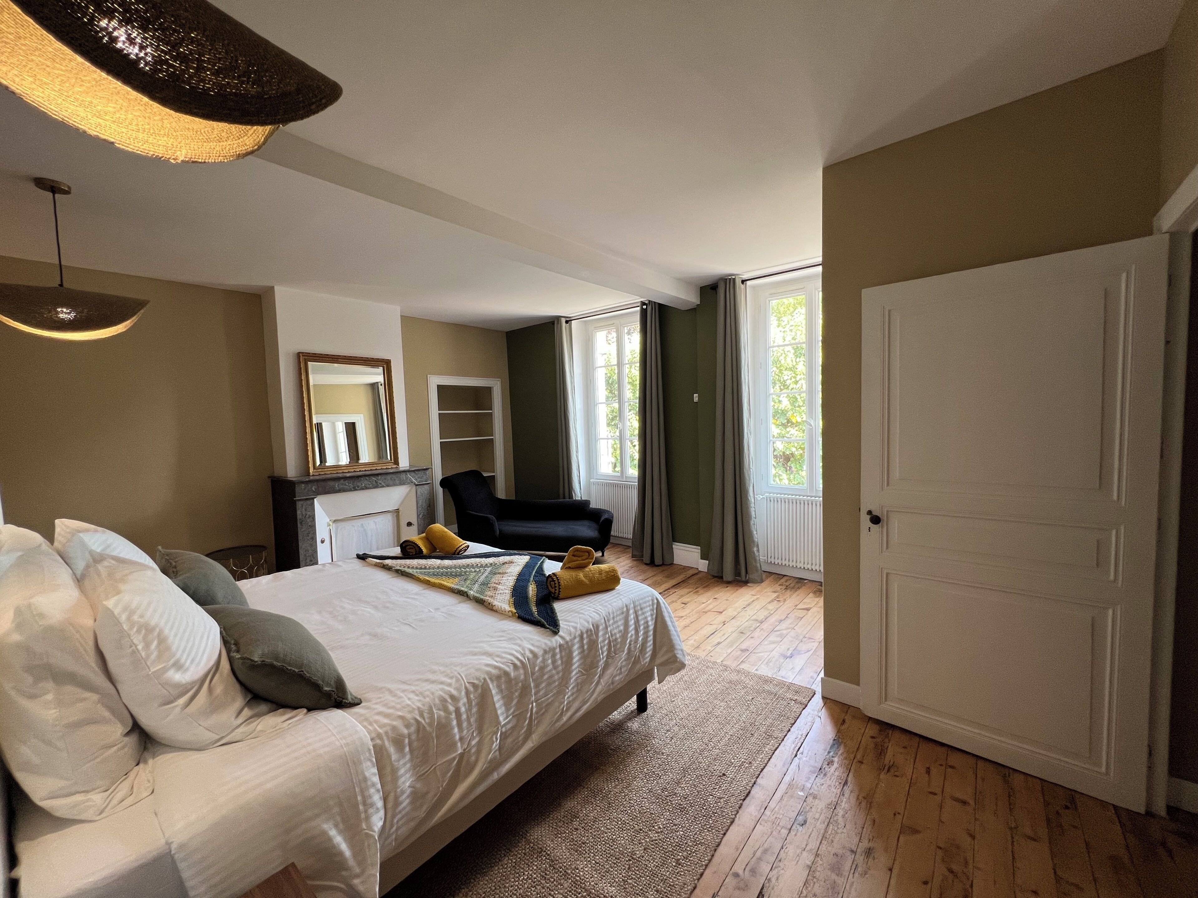 Un dormitorio con una cama grande, una silla, un tocador y una puerta.