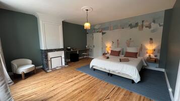 Une chambre à coucher avec un lit, des lampes de chevet, une chaise, un bureau et une cheminée.