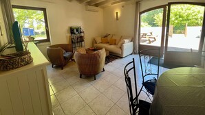 A living room with a sofa, chairs, a coffee table, a bookshelf, and a large window. - Domaine Bardon (Chaunac)