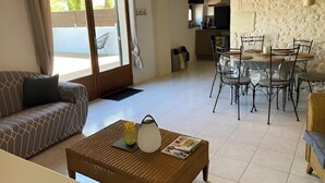 A living room with a sofa, a coffee table, and a dining area with chairs and a table. - Domaine Bardon (Chaunac)
