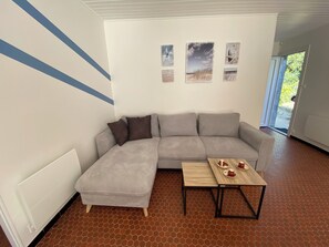 Una sala de estar moderna con un sofá seccional gris, una mesa de centro de madera y piso de baldosas.