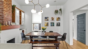 A dining area with a wooden table, black chairs, a bench, a hanging light fixture, and wall art. - Heritage Glam Home BBQ + Patio Parking DT (St. John's)