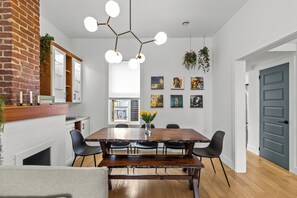 A dining area with a wooden table, black chairs, a bench, a hanging light fixture, and wall art. - Heritage Glam Home BBQ + Patio Parking DT (St. John's)
