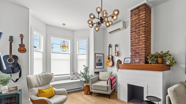 A living room with a fireplace, a large window, and a guitar wall. - Heritage Glam Home BBQ + Patio Parking DT (St. John's)