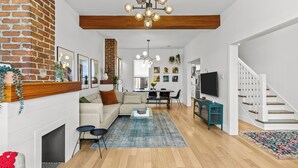 A spacious living room with a fireplace, a sofa, a coffee table, and a staircase. - Heritage Glam Home BBQ + Patio Parking DT (St. John's)