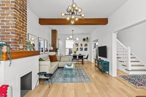 A spacious living room with a fireplace, a sofa, a coffee table, and a staircase. - Heritage Glam Home BBQ + Patio Parking DT (St. John's)