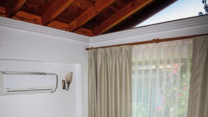 Un dormitorio con cabecera de madera, una cama con ropa de cama blanca, una mesita de noche con un teléfono y una ventana con cortinas.
