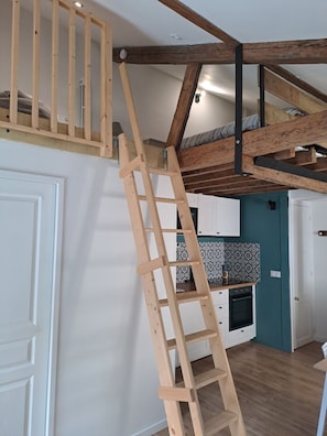 A loft bedroom with a wooden ladder, exposed wooden beams, a bunk bed, and a kitchenette. - Hyper-center - Beach on foot - Cosy accommodation (Villers-sur-Mer)