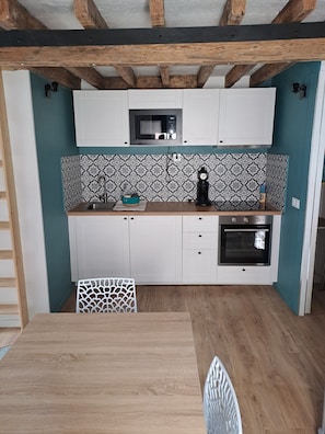 A kitchen with white cabinets, a microwave, a clock, and an oven. - Hyper-center - Beach on foot - Cosy accommodation (Villers-sur-Mer)