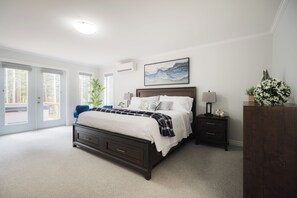 A bedroom with a large bed, a nightstand, a dresser, a window with a view, and a ceiling light. - Birch Grove Chalet, Hot Tub, Golf, Private Forest (Humber Valley Resort)