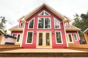 A red two-story house with a front porch, large windows, and a chimney.