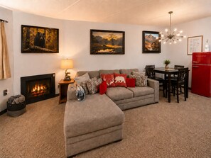 Ein Wohnzimmer mit Kamin, einer Couch, einem Esstisch und einem roten Kühlschrank.