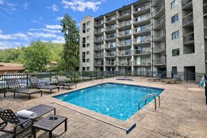 Ein Swimmingpool mit Liegestühlen und ein mehrstöckiges Gebäude im Hintergrund.