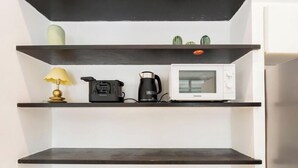 Una cocina con microondas, cafetera y una lámpara en un estante.