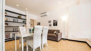 Una sala de estar moderna con un sofá blanco, una mesa de comedor con sillas y una lámpara de pie.