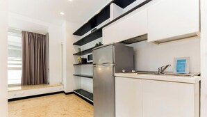 Una cocina pequeña con refrigerador, microondas y lavamanos.
