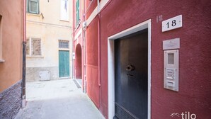 A narrow alleyway with a red building, a door with a number plate, and a small sign on the wall. - Beach 1m| 4 People| Sea Apartment by Tilo (Sestri Levante)