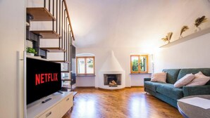 A living room with a fireplace, a sofa, a TV, and a staircase. - Bocadasse Beach| Parking| Wifi| By Tilo (Genoa)