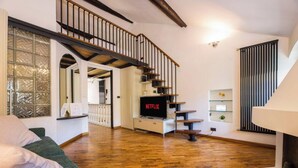 A living room with a staircase, a TV, and a bookshelf. - Bocadasse Beach| Parking| Wifi| By Tilo (Genoa)