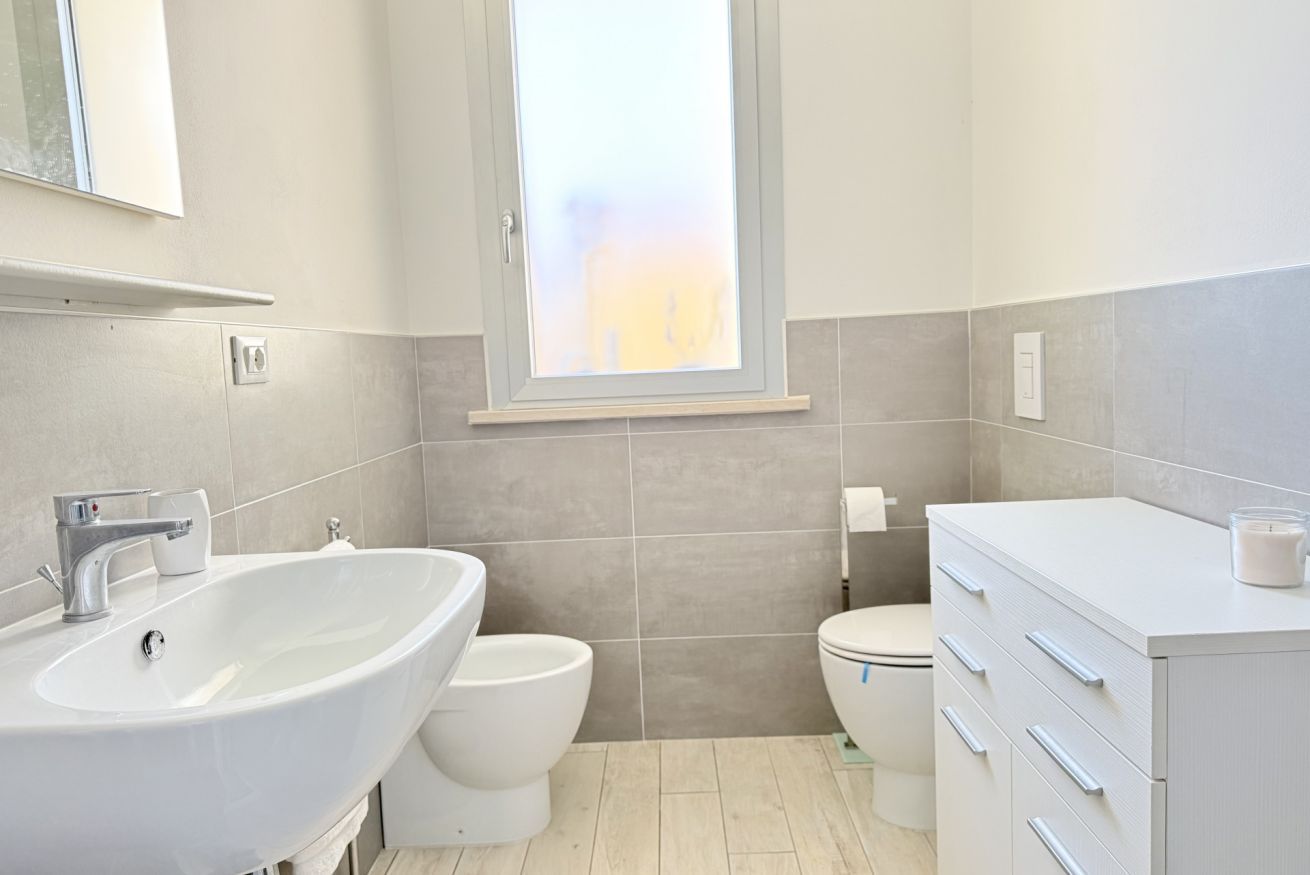 A bathroom with a white sink, a toilet, and a cabinet.