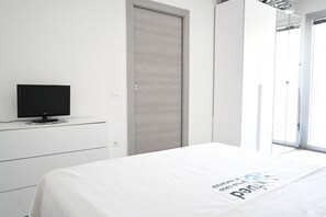 Una habitación de hotel con una cama, un televisor en una cómoda, una puerta y una ventana.
